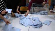 Electoral workers begin to count ballots at a polling station following municipal elections across Turkiye, in Istanbul on March 31, 2024. (Photo by YASIN AKGUL / AFP)
