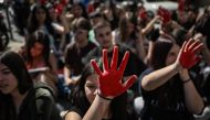 Students from a musical school hold their red painted hands in the air outside a police station during a demonstration against police inaction in feminicides in Athens on April 5, 2024. (Photo by Aris MESSINIS / AFP)
