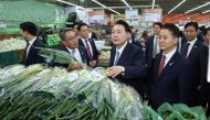This picture taken on March 18, 2024 shows South Korean President Yoon Suk Yeol (C) visiting a Hanaro Mart branch to check the price of green onions in Seoul. Photo by YONHAP / AFP