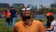 The Dome of the U.S. Capitol Building is visible as Johnny Marshall, of Brandywine, Maryland, (Foreground) views the partial solar eclipse at Gravelly Point Park on April 8, 2024 in Arlington, Virginia. (Photo by Andrew Harnik / GETTY IMAGES NORTH AMERICA / Getty Images via AFP)
