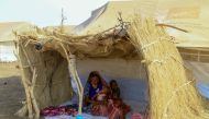 (FILES) A picture taken on March 20, 2024, shows a displaced woman and her children sitting in the shade of a straw hut at a camp in southern Gadaref state for people who fled Khartoum and Jazira states in war-torn Sudan. (Photo by AFP)

