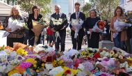 Australian Prime Minister Anthony Albanese (C) stands with New South Wales Premier Chris Minns (4th R) and other officials as they prepare to leave flowers outside the Westfield Bondi Junction shopping mall in sydney on April 14, 2024. (Photo by DAVID GRAY / AFP)
