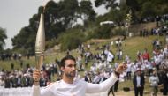 First torch bearer, rowing Olympic gold medalist on 2020, Stephanos Ntouskos, runs with the Olympic torch during the lighting ceremony for the Paris 2024 Olympics Games at the Ancient Olympia archeological site, birthplace of the ancient Olympics in southern Greece, on April 16, 2024. (Photo by Angelos Tzortzinis / AFP)