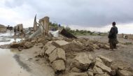 Residents gather beside a damaged house after heavy rains on the outskirts of Chaman in Balochistan province on April 19, 2024. At least 65 people have died in storm-related incidents including lightning in Pakistan, officials said, with rain so far in April falling at nearly twice the historical average rate. (Photo by Abdul BASIT / AFP