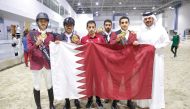 Qatar equestrian team's riders and Director of the Qatar Equestrian Teams Abdullah Al Marri pose with the national flag.   