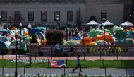 A woman walks past Israeli and US flags alongside portraits of Israelis taken hostage by the militant Palestinian group Hamas in front of the pro-Palestinian encampment at the Columbia University on April 28, 2024 in New York City. Photo by Charly TRIBALLEAU / AFP. 