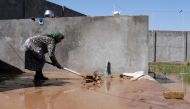 An Afghan woman cleans the courtyard of her house covered in wet mud following flash floods in Herat on May 5, 2024. Photo by Mohsen KARIMI / AFP.