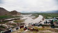 Afghan people gather along a road before a floaded area between Samangan and Mazar-i-Sharif following a flash flood after a heavy rainfall in Feroz Nakhchir district of Samangan Province on May 11, 2024. (Photo by Atif Aryan / AFP)
 