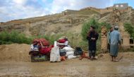 Afghan men stand beside their belongings kept near a damaged house after flash floods following heavy rainfall in Firozkoh, Ghor province on May 18, 2024. Flash flooding has killed at least 50 people in western Afghanistan, provincial police said on May 18, a week after hundreds were washed away in the north of the country. (Photo by AFP)
