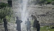 Youths cool off as water bursts out from a damaged water pipe line amidst a heatwave in Karachi on May 21, 2024. (Photo by Asif HASSAN / AFP)