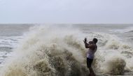 A man reacts as high tidal waves hit the coast along a sea beach during rainfall in Kuakata on May 26, 2024, ahead of cyclone Remal's landfall in Bangladesh. (Photo by Munir Uz Zaman / AFP)