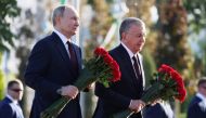 In this pool photograph distributed by the Russian state agency Sputnik, Russia's President Vladimir Putin (left) and Uzbekistan's President Shavkat Mirziyoyev attend a flower laying ceremony at the 