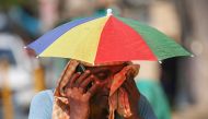 A vendor with an umbrella over his head talks on mobile phone as he wipes his face with a cloth on a hot summer day in Varanasi on May 27, 2024. Photo by Niharika KULKARNI / AFP