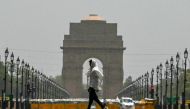 A man wears a scarf as he walks past the India Gate on a hot summer day in New Delhi on June 18, 2024. (Photo by Arun Sankar / AFP)