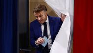 French President Emmanuel Macron leaves the voting booth prior to cast his vote in the first round of parliamentary elections at a polling station in Le Touquet, northern France on June 30, 2024. Photo by Yara Nardi / POOL / AFP.