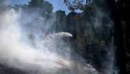 A firefighter works to extinguish a wildfire in Keratea, near Athens, on June 30, 2024. (Photo by Aris MESSINIS / AFP)

