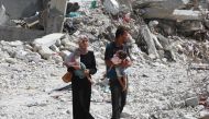 A Palestinian couple holds their children as they walk through debris in Khan Yunis in the southern Gaza Strip on July 4, 2024. (Photo by Bashar TALEB / AFP)
