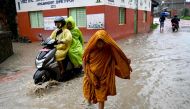 People wade through flood after Hanumante river overflowed following heavy rain in Bhaktapur on July 6, 2024. (Photo by Prakash Mathema / AFP)