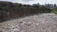 People stand on the edge of a dumpsite where six bodies were found at the landfill in Mukuru slum, Nairobi, on July 12, 2024. (Photo by Simon Maina / AFP) 