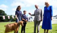 Britain's King Charles III (2nd R) and Britain's Queen Camilla (R) meet a Golden Guernsey goat during a tour of Les Cotils at L'Hyvreuse, in St Peter Port, Guernsey on July 16, 2024 as part of their two day official visit to the Channel Islands. (Photo by Andrew Matthews / POOL / AFP)