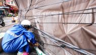 A shop owner tightens canvas around his booth to prevent possible damage as Typhoon Gaemi approaches, in Yilan on July 24, 2024. (Photo by I-Hwa Cheng / AFP)
 