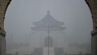 A visitor (bottom R) takes photographs in front of the Chiang Kai-shek Memorial Hall in heavy rain from weather patterns caused by Typhoon Gaemi in Taipei on July 24, 2024. (Photo by Sam Yeh / AFP)
