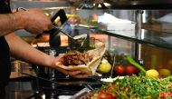 An employee prepares a doner with meat from a kebab skewer in a doner restaurant in the city centre of Dortmund, western Germany on July 26, 2024. (Photo by Ina FASSBENDER / AFP)
