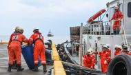 Crew of a private company loads a barrel of oil spill dispersant to be used in the oil spill response, at a port in Limay, Bataan on July 26, 2024. (Photo by Jam Sta Rosa / AFP)
 