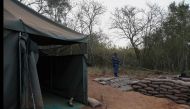 A armed South African Police Services (SAPS) officer stands near the entrance to a farm where they detained ninety five Libyan nationals for receiving training at what authorities suspect to be a secret military camp in White River, Mpumalanga province on July 27, 2024. (Photo by Phill Magakoe / AFP)
