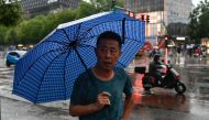 A man holding an umbrella walks during a rainstorm in Beijing on July 30, 2024. Photo by Pedro PARDO / AFP.
