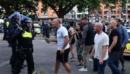 A protester holding a piece of concrete walks towards riot police as clashes erupt in Bristol on August 3, 2024 during the 'Enough is Enough' demonstration held in reaction to the fatal stabbings in Southport on July 29. (Photo by JUSTIN TALLIS / AFP)
