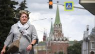 A woman walks in front of the Kremlin (seen in the background) in Moscow on July 29, 2024. (Photo by Alexander NEMENOV / AFP) 