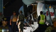 A Colombian migrant, with his hands and feet handcuffed, climbs a plane at the Albrook Gelabert airport in Panama City on August 20, 2024, during his deportation. (Photo by ARNULFO FRANCO / AFP)
