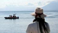 A woman watches rescue teams at work in Porticello near Palermo, on August 21, 2024 two days after the British-flagged luxury yacht Bayesian sank. Photo by Alberto PIZZOLI / AFP.