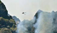 A Regional Civil Protection Service helicopter fights a wildfire raging through Pico do Areeiro mountain on August 21, 2024 in Santana on the Portuguese island of Madeira, which broke out one week ago in the Ribeira Brava district. (Photo by Helder Santos / AFP)
