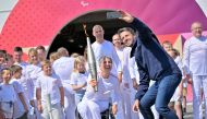 French President of the Paris 2024 Olympics and Paralympics Organising Committee (COJO) Tony Estanguet (right) takes a selfie with former French wheelchair fencer Emmanuelle Assmann holding the torch of the Paris 2024 Paralympic Games after arrival of the Paralympics flame at the entrance of the Channel Tunnel in Coquelles, northern France on August 25, 2024. (Photo by Lou Benoist / AFP)