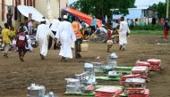 Sudanese, displaced from the town of Sinjah, receive humanitarian aid at their makeshift camp in the eastern city of Gedaref on August 22, 2024. (Photo by Ebrahim Hamid / AFP)

