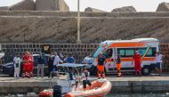 Italian Carabinieri stand on the quay with health workers look at a Coast Guard boat prepares to search for six others missing after recovering a victim due to a sailboat sank off the coast of Porticello, nosthwestern of Sicily Island, on August 19, 2024. (Photo by Igor Petyx / ANSA / AFP)

