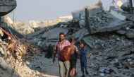  Ahmad Abu Amsha, 42, a music teacher who had to flee Beit Hanun in the northern Gaza Strip, walks in a war-devastated area in Khan Yunis on his way to entertain displaced Palestinian children by playing songs on his guitar on September 1, 2024. (Photo by Bashar TALEB / AFP)
