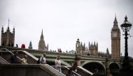 Pedestrians walk along the Southbank of the River Thames, with the Elizabeth Tower, commonly known by the name of the clock's bell 
