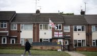 Photo used for demonstration purposes. A woman walks past a house displaying two St George's Cross flags in Leeds, northern England on September 4, 2024. Photo by Oli SCARFF / AFP.