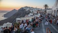Tourists take pictures of the sunset in the village of Fira on the Greek island of Santorini on July 19, 2024. Photo by Aris Oikonomou / AFP