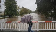 A man shelters from the rain under an umbrella as he runs over the bridge on September 14, 2024 in Krnov city as Central Europe faces heavy rainfall expected to cause floods. Photo by Michal Cizek / AFP.