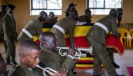 Uganda People's Defense Forces (UPDF) officers play musical instruments and place the coffin of Ugandan marathon runner Rebecca Cheptegei, 33, in the middle of the common room for people to pay their respects and mourn her in the district headquarters of the village of Bukwo on September 14, 2024. Photo by BADRU KATUMBA / AFP.