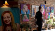A customer walks past portrait paintings of Italy's Prime Minister Giorgia Meloni adorning the wall of 