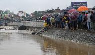 Residents stand along a street as they inspect flood waters after the Bagmati river overflowed during monsoon rains in Kathmandu on September 28, 2024. (Photo by Prakash Mathema / AFP)
 