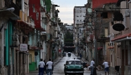 People walk along a street during the fourth day of a massive power outage in Havana on October 21, 2024. Photo by YAMIL LAGE / AFP