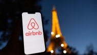 This photograph taken on October 28, 2024 shows the logo of short-term housing rentals online application Airbnb on a smart-phone screen in front of the Eiffel Tower in Paris. Photo by Grégoire CAMPIONE / AFP