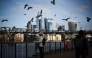 File photo: Seagulls fly over people walking on the Southbank of the River Thames backdropped by the business and financial district in central London on November 15, 2024. Photo by HENRY NICHOLLS / AFP.