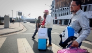 Shoppers walk across the street with their purchases near the US-Mexico border in San Ysidro, California, on November 26, 2024. (Photo by Sandy Huffaker / AFP)
